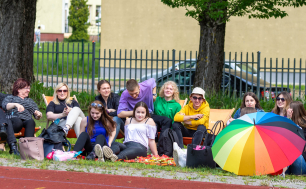 Na zdjęciu widać uczniów z nauczycielką siedzących na leżakach i kocach na szkolnym podwórku.